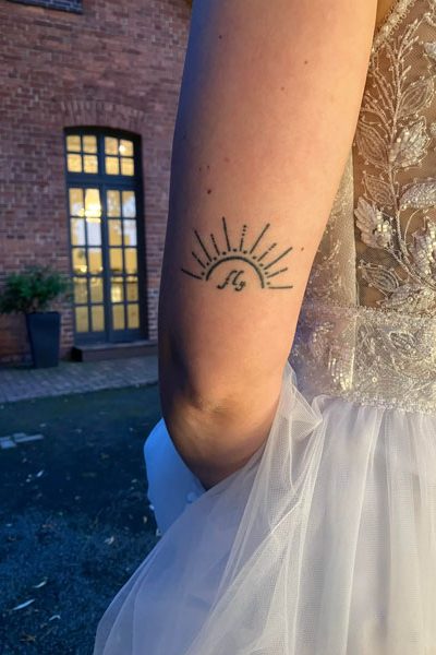 Beitragsbild der Podcastfolge_O-3 / Kreative Schöpfung, die sich in der realen Welt manifestiert _ Offen Gesprochen... über Gott und die Welt mit Martin Kolodziej und Alwina Simon - Ich & DU, Martin - Wow Sessions, ein Podcast über das Leben an sich // Zu sehen ist der linke Arm einer Braut in einem weißen Brautkleid, allerdings von hinten. Darauf ist ein Tattoo mit Sonnenstrahlen abgebildet, die das Wort „fly“ umspielen. // Credits: Privater Bildbestand von Alwina Simon – 2024-06-01