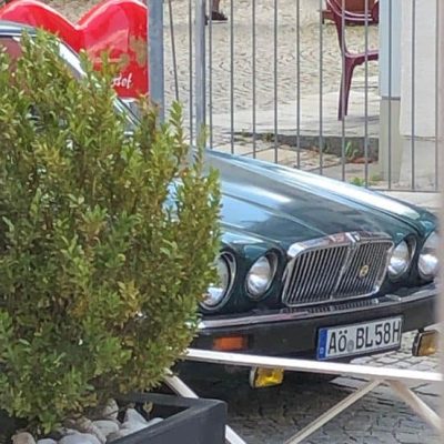 Dunkelgrüner Oldtimer mit dem Kennzeichen AÖ BL 58 H, geparkt vor einem Eiscafé bei der Gnadenkapelle in Altötting.